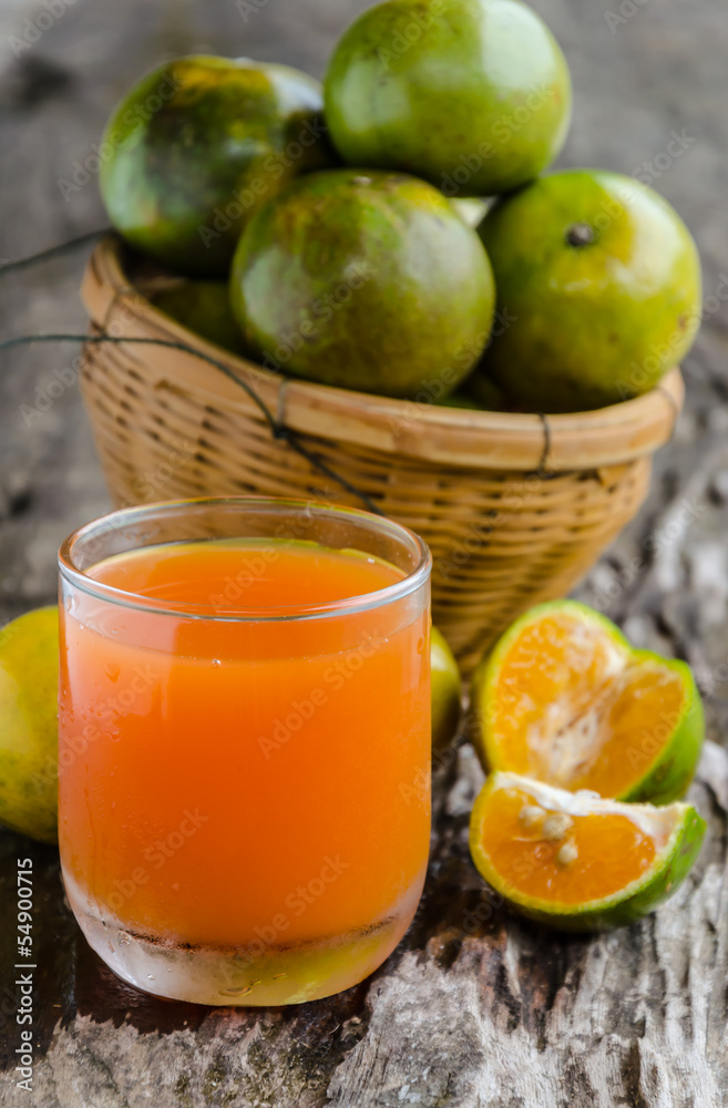 a glass of orange juice and basket on wooden background. a glass of orange juice and basket on wooden background.