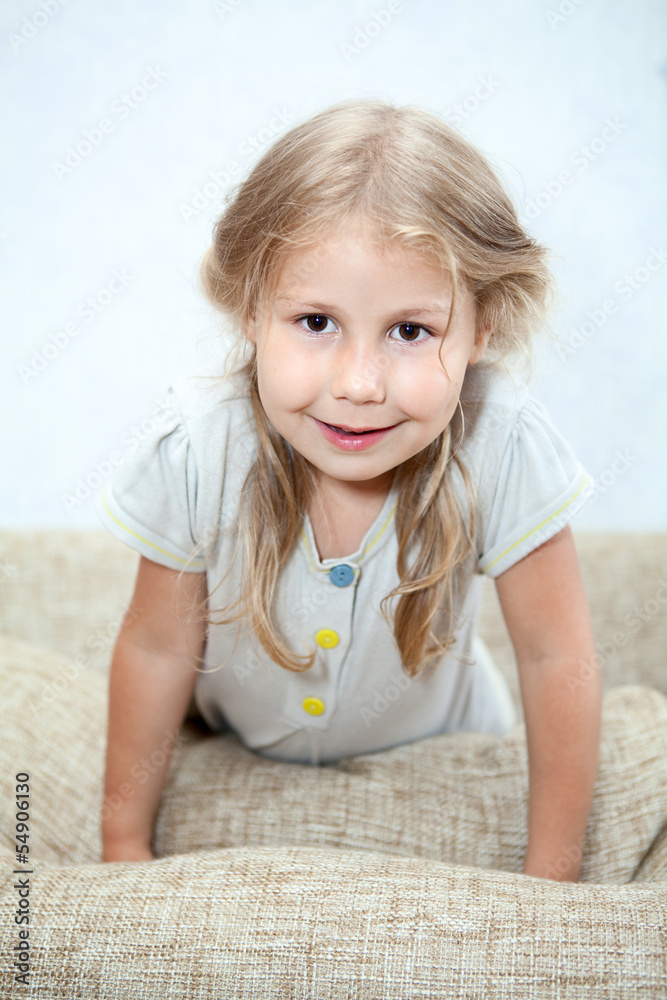 Playful Caucasian girl sitting on sofa pillows Playful Caucasian girl sitting on sofa pillows