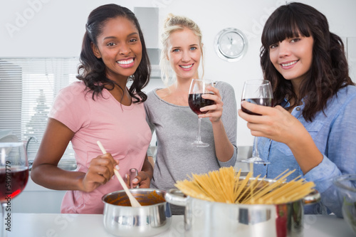 Cheerful friends making spaghetti dinner together and drinking r photo