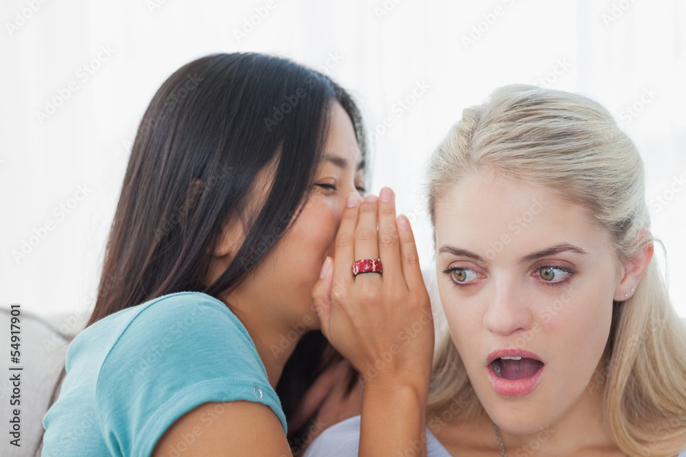 Friend telling secret to blonde woman Friend telling secret to blonde woman