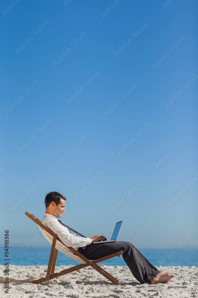 Young businessman on his deck chair using his laptop