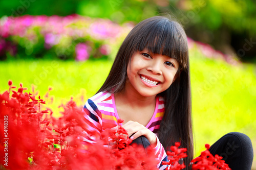 Closeup smiling little asian girl sitting on flower field