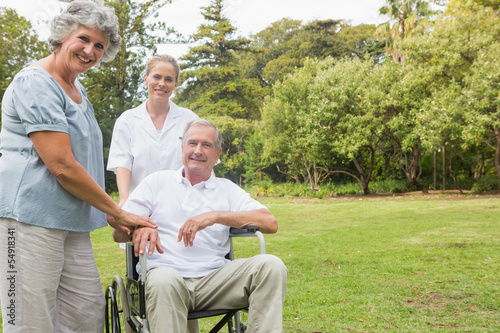 Cheerful man in a wheelchair with his nurse and wife