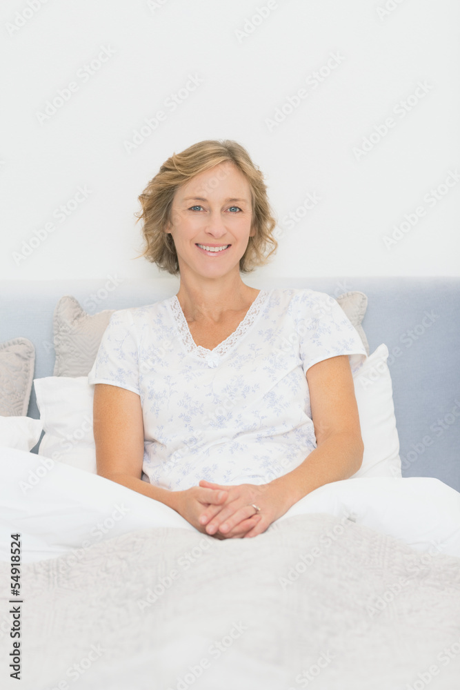 Blonde happy woman sitting in bed smiling at camera Blonde happy woman sitting in bed smiling at camera