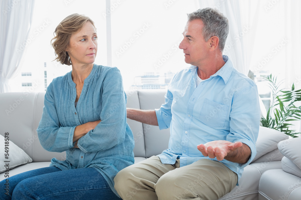 Fototapeta premium Middle aged couple sitting on the sofa having a dispute