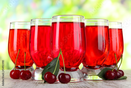 Glasses compote on wooden table on nature background