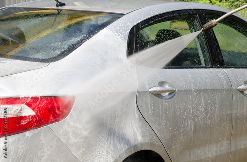 Manual car washing cleaning with foam and pressured water at ser