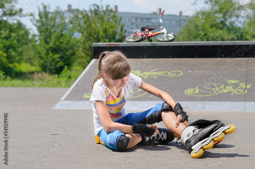 Young girl wearing rollerblades massaging her calf