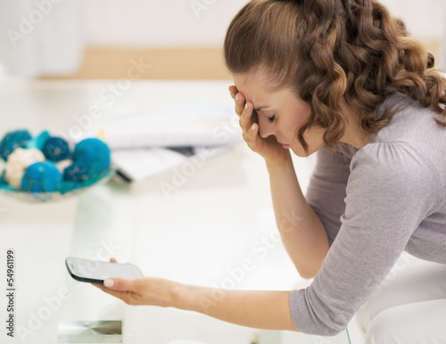 Stressed young woman holding cell phone