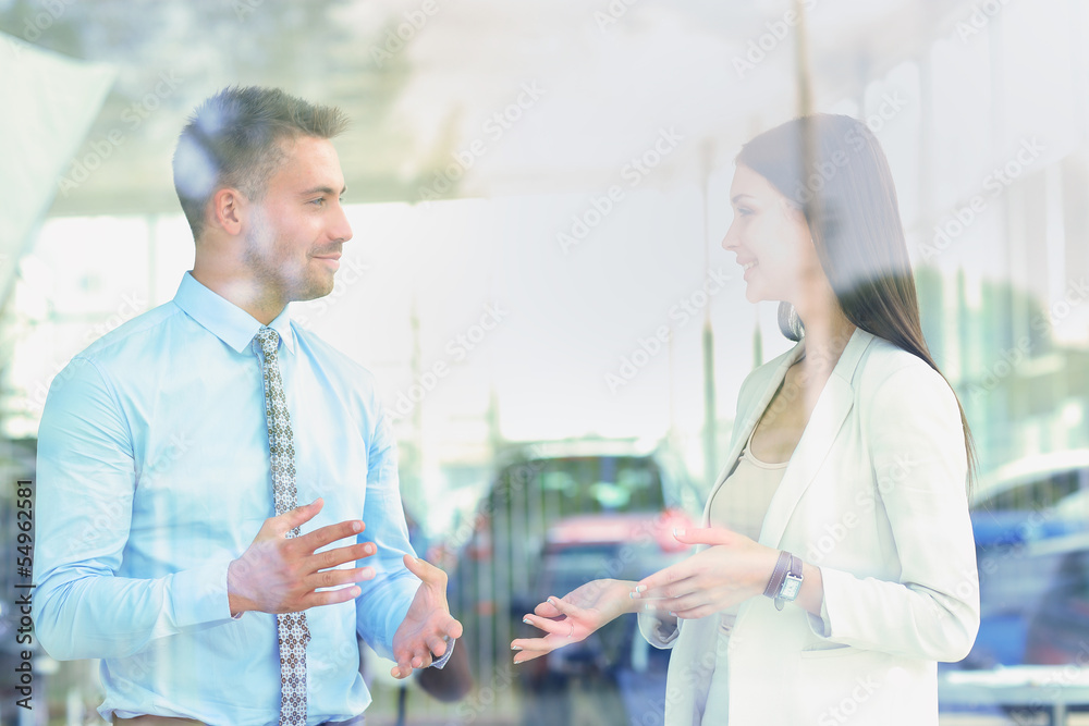 Fototapeta premium Two cheerful smiling young businesspeople talking at the office.