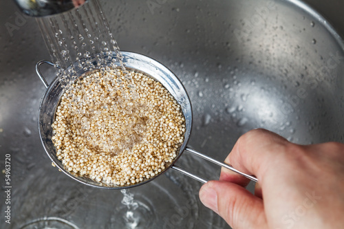 Man holding small collander rins raw quinoa seeds photo