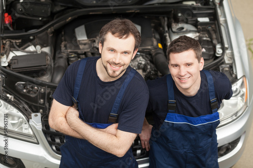 Confident mechanics. Top view of two cheerful auto mechanics loo
