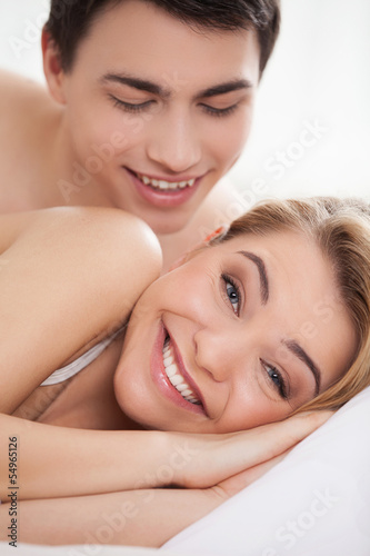 Loving couple in bed. Happy young loving couple lying on bed whi