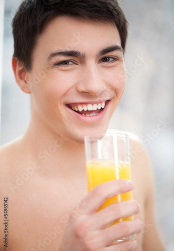 Men drinking juice. Portrait of cheerful young man holding a gla