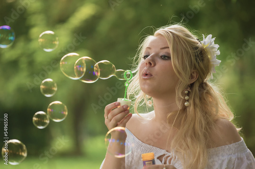 The young blonde blows soap bubbles