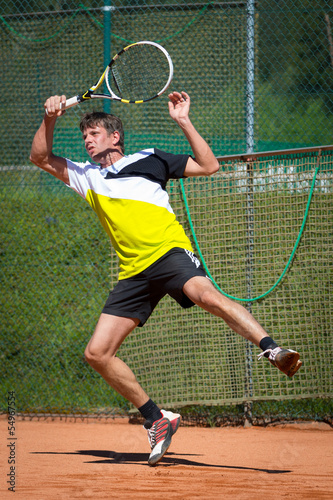 tennis player jumps after playing forehand ball