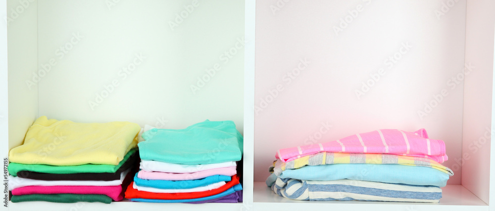Clothes neatly folded on shelves Clothes neatly folded on shelves