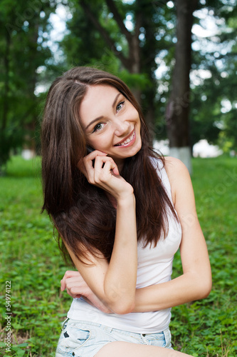 Smiling young woman talking mobile outdoor