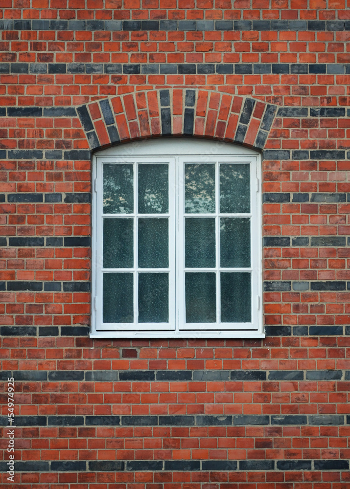White painted wood arched window in a red brick wall