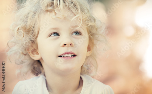 Blonde baby girl smiling outdoor. Closeup vintage portrait