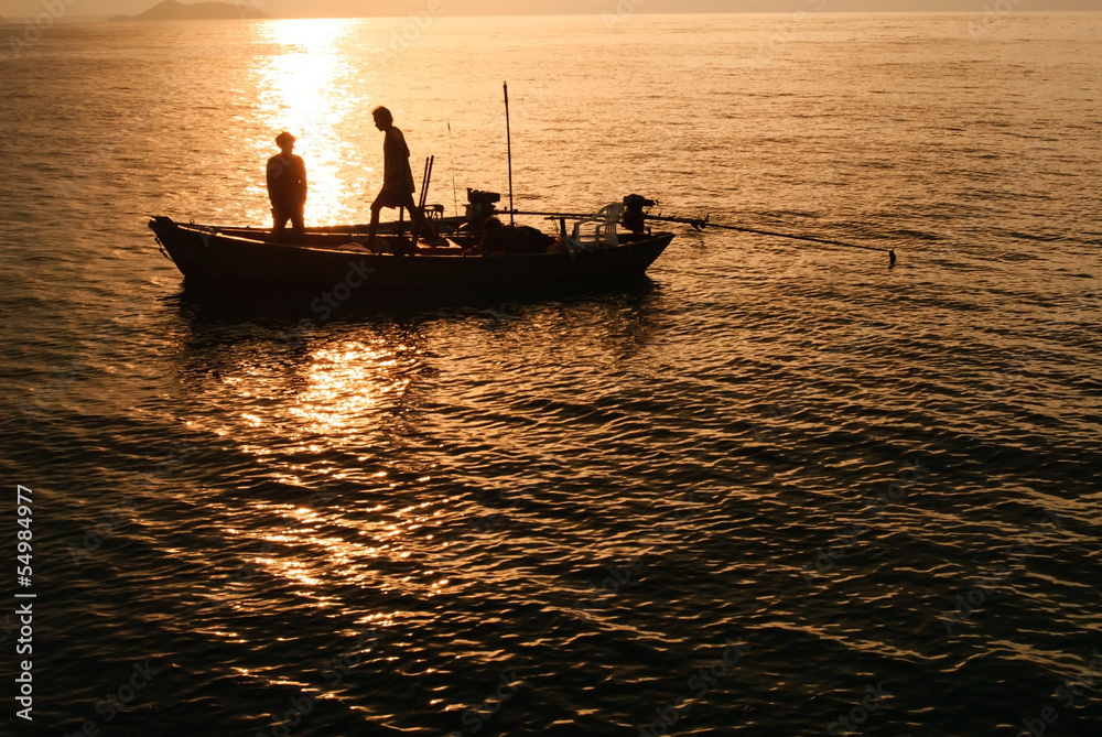 Silhouettes fishing boats and fisherman in the sea after sunset