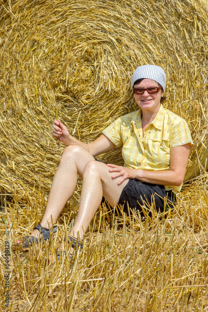 Organic farmer sitting in front of bales of straw Organic farmer sitting in front of bales of straw
