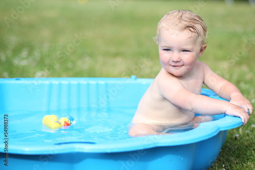 Sweet baby girl playing with water in kiddie pool