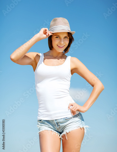 girl in hat standing on the beach