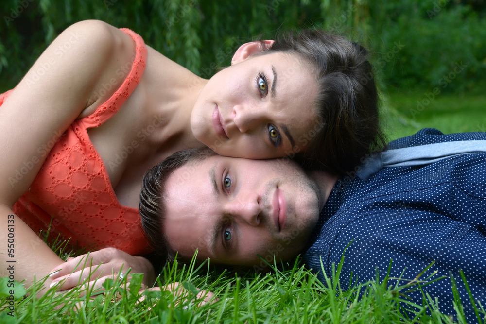 Young couple laying on grass in a garden setting Young couple laying on grass in a garden setting