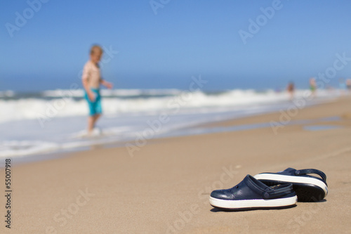 Slippers lying on sand and boy playing