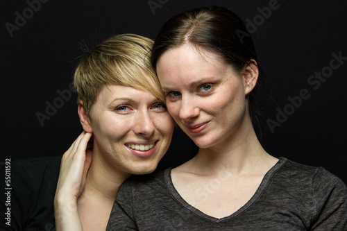 Girlfriends pose against black background, horizontal