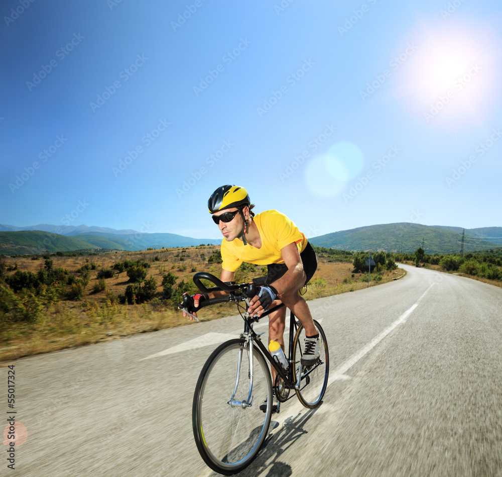 Male cyclist riding a bike on an open road on a sunny day