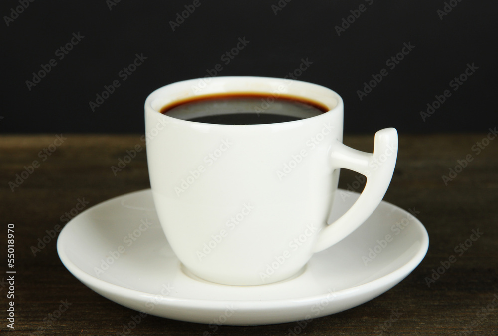 Cup of coffee on wooden table on black background