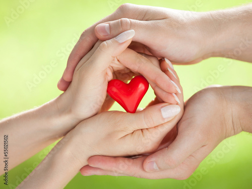 Hands of man and woman holding red heart