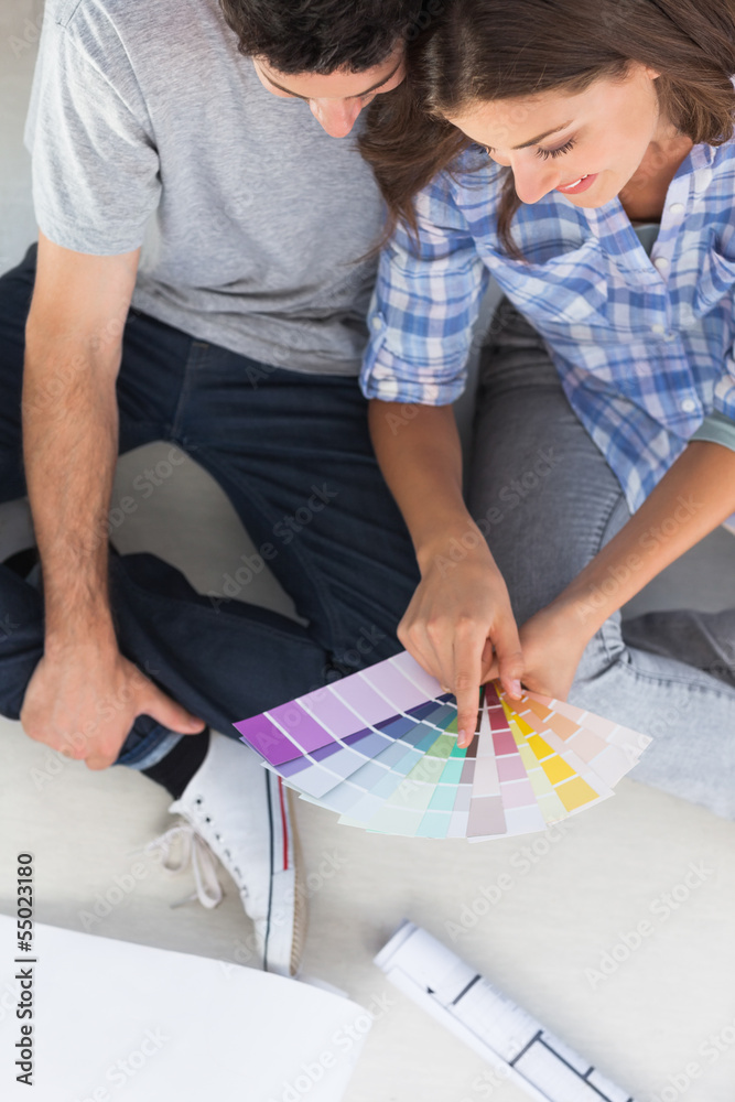 Woman pointing at color charts sitting in her new house Woman pointing at color charts sitting in her new house