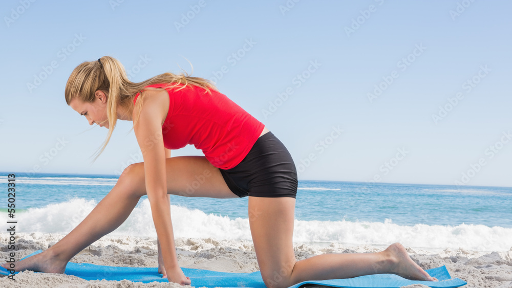 Fit blonde stretching leg on exercise mat Fit blonde stretching leg on exercise mat