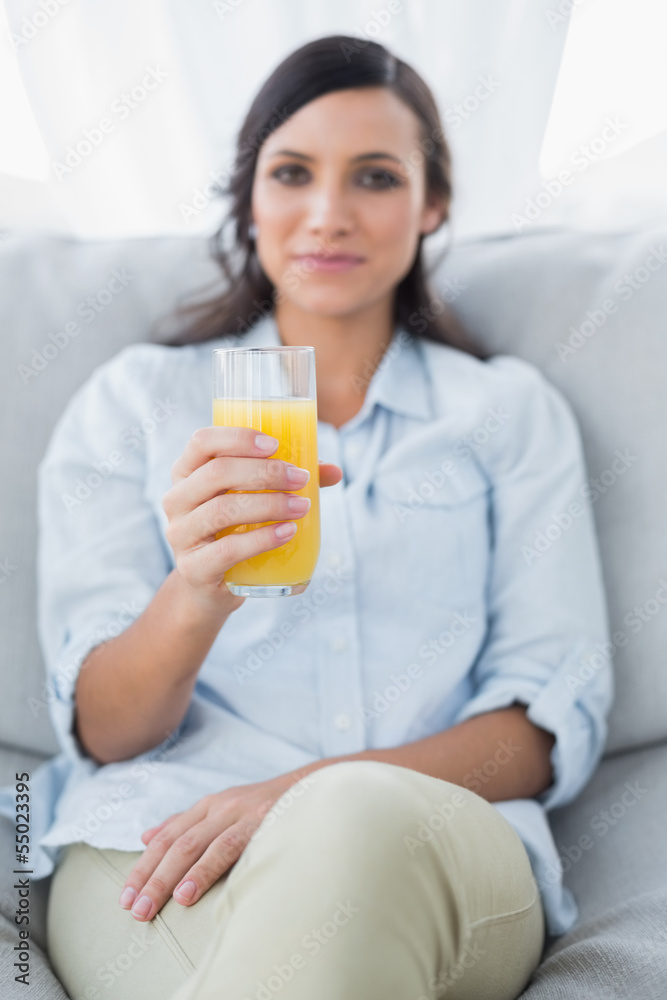 Peaceful brunette offering orange juice to camera Peaceful brunette offering orange juice to camera