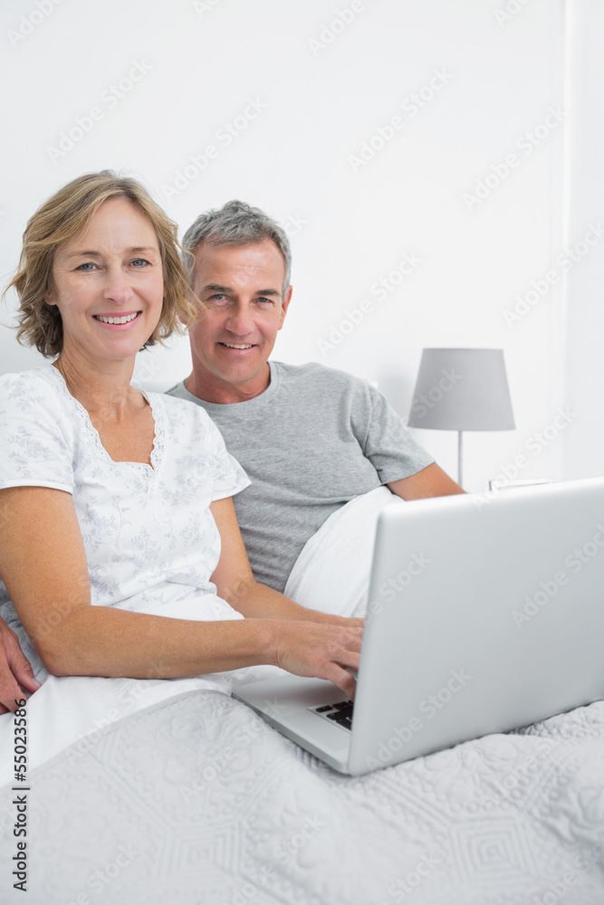 Middle aged couple using their laptop together in bed Middle aged couple using their laptop together in bed