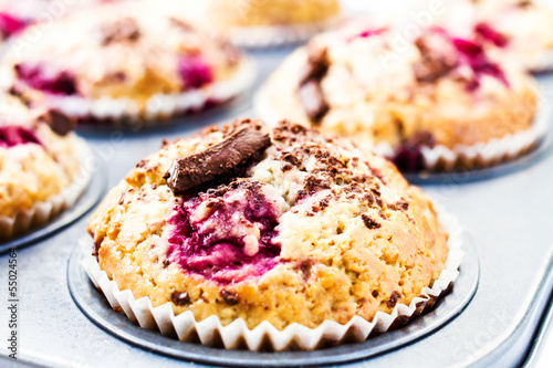 Festive chocolate small cakes with cherry in baking tray. Close