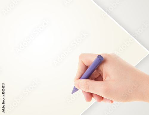 Child drawing with colorful crayon on empty blank paper