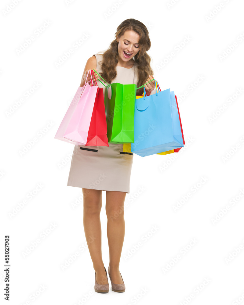 Full length portrait of happy young woman checking shopping bags
