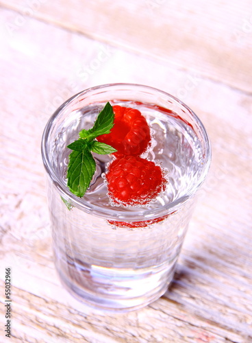 Water in glass with mint and two raspberries