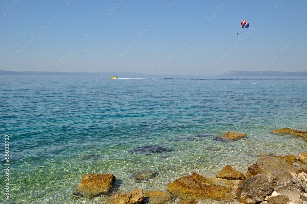 Paraglider on the sky dragged by boat, under amazing beach Paraglider on the sky dragged by boat, under amazing beach