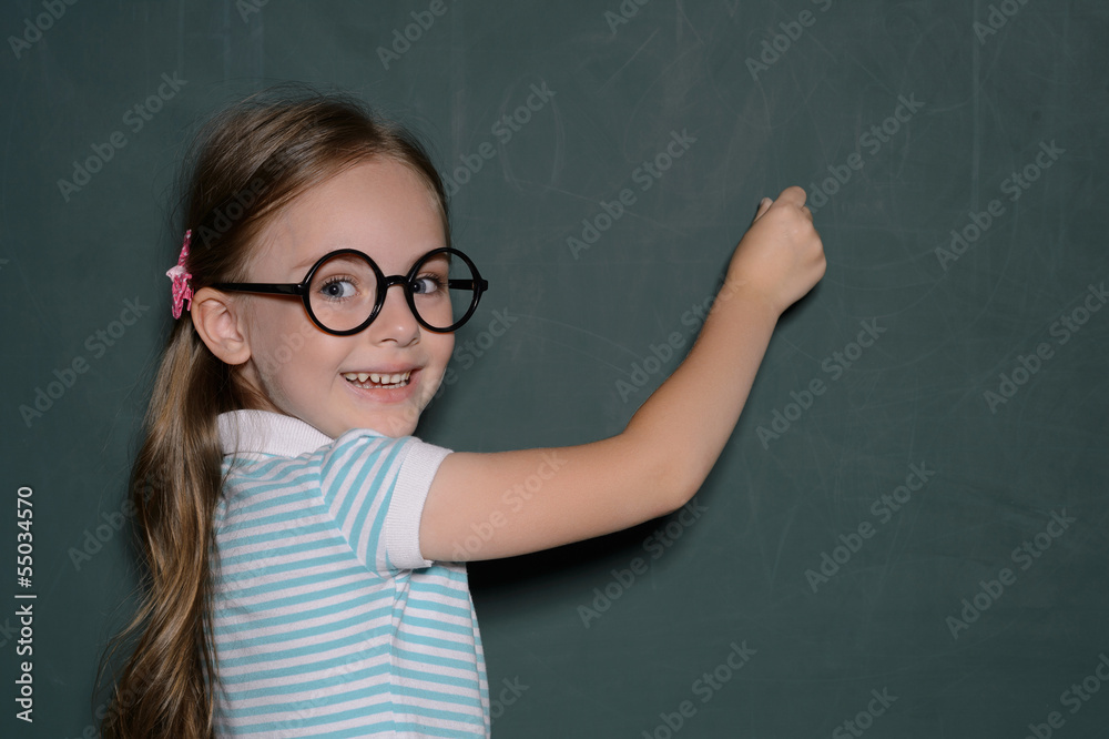 Happy schoolgirl. Cheerful little schoolgirl in glasses standing