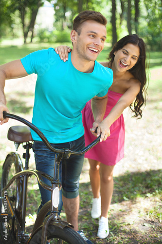 Couple in spring park. Cheerful young couple with bicycle having