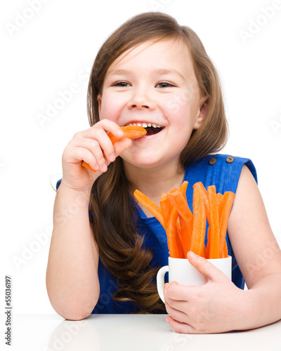 Cute little girl is eating carrot