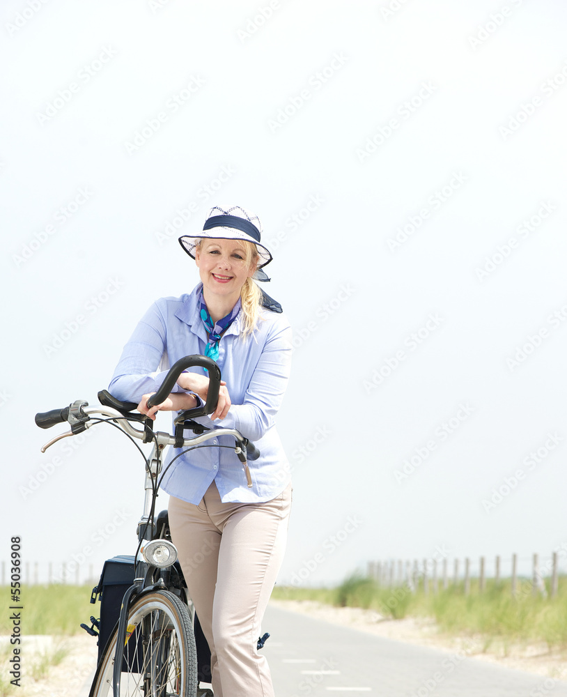 Obraz premium Happy mature woman relaxing with bike on a summer day