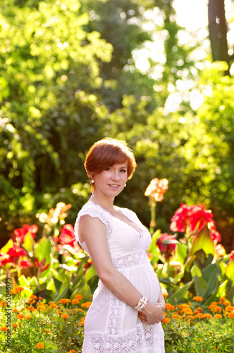 Beautiful pregnant woman in green garden