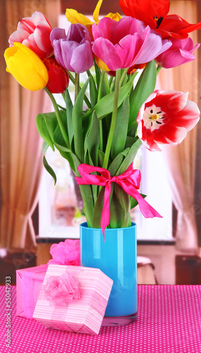 Fototapeta Naklejka Na Ścianę i Meble -  Beautiful tulips in bouquet with gifts on table in room