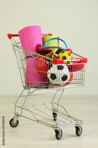 Shopping cart with sport equipment, on gray background